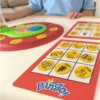 Отблизо се виждат жетони с картинки и карти за игра от настолната игра Woopie Bingo!.